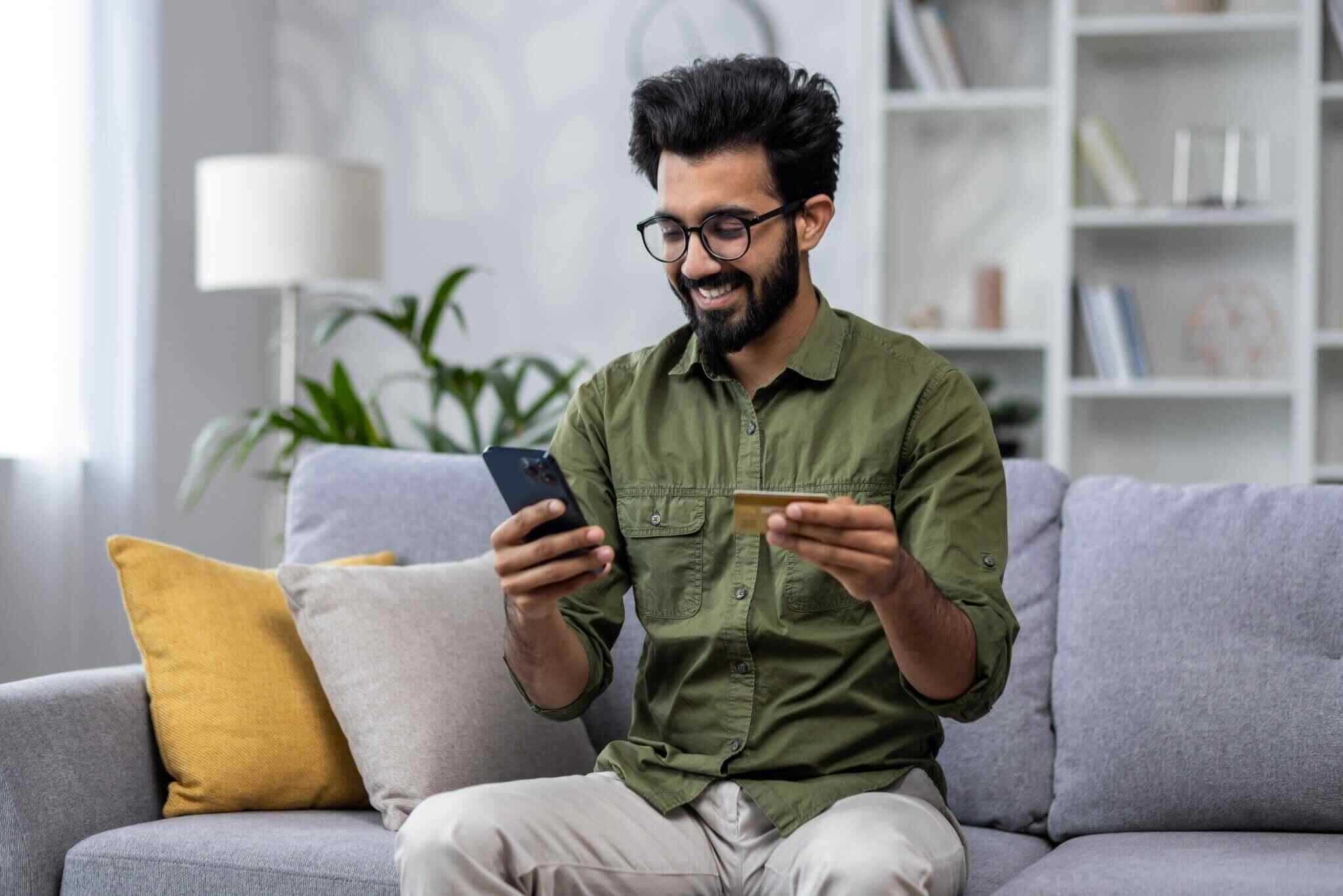 satisfied man shopping online sitting on sofa at home