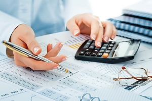 women hands holding a pen and using a calculator 