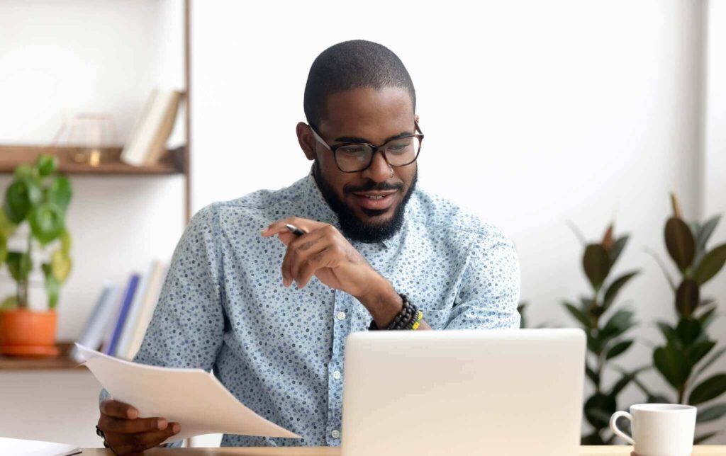 Focused african american businessman working with laptop documents in office