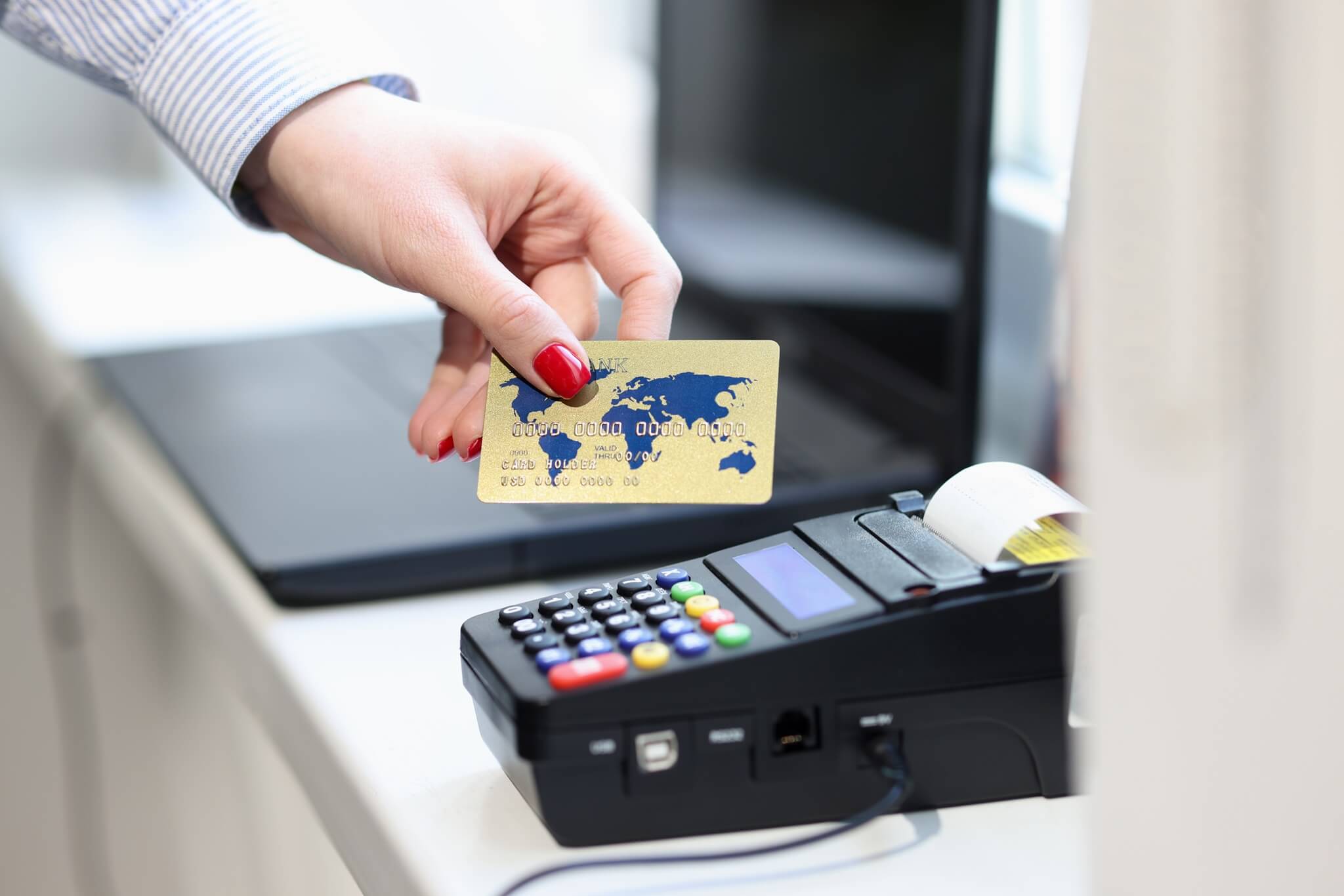 female hand holding credit bank card near pos terminal closeup
