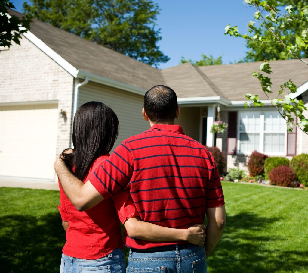 happy couple standing in front of their home