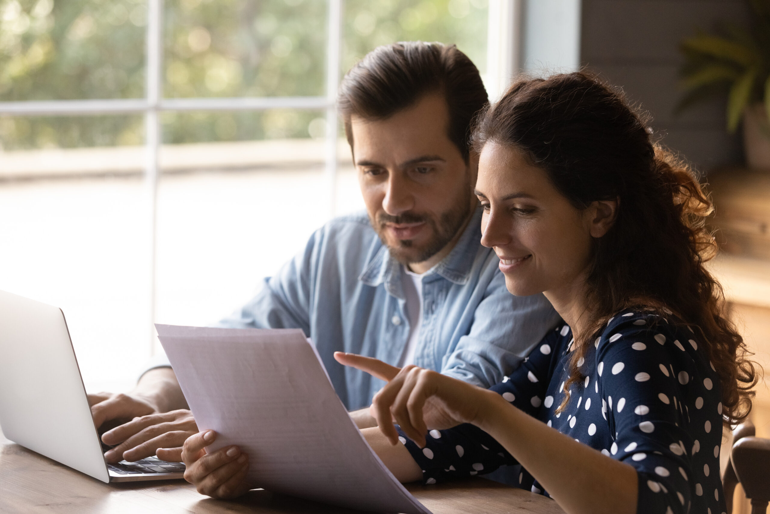 man and woman reviewing documents and using a laptop computer