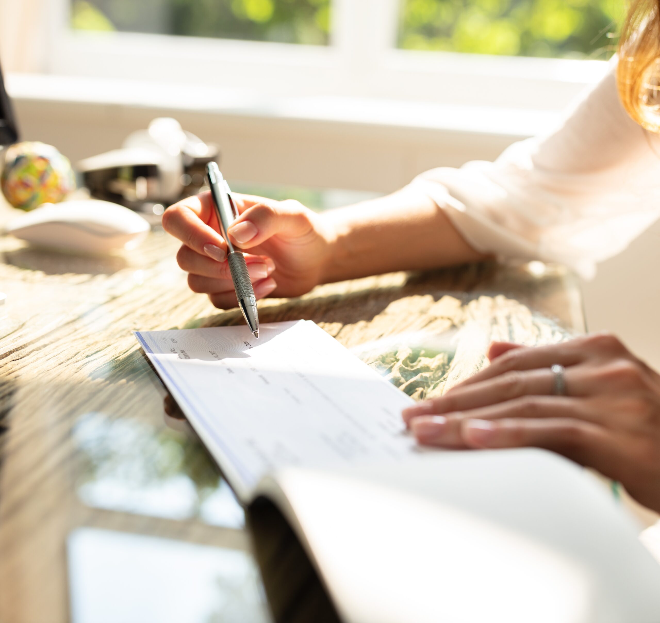 women writing a check sitting at a desk