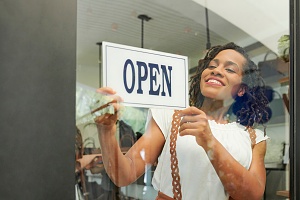 young black women turning her store open sign