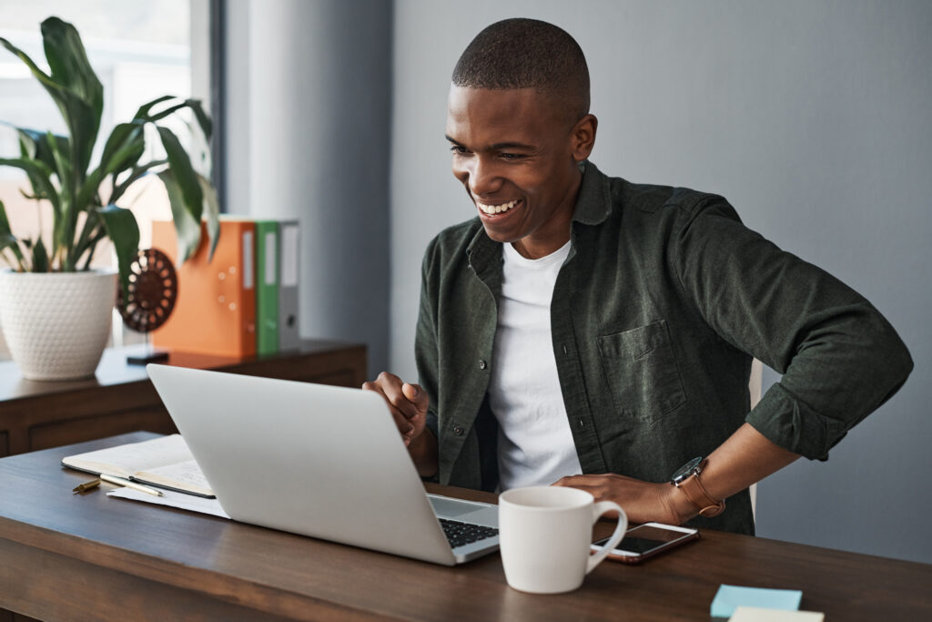 young man in a green button down shirt using a laptop.