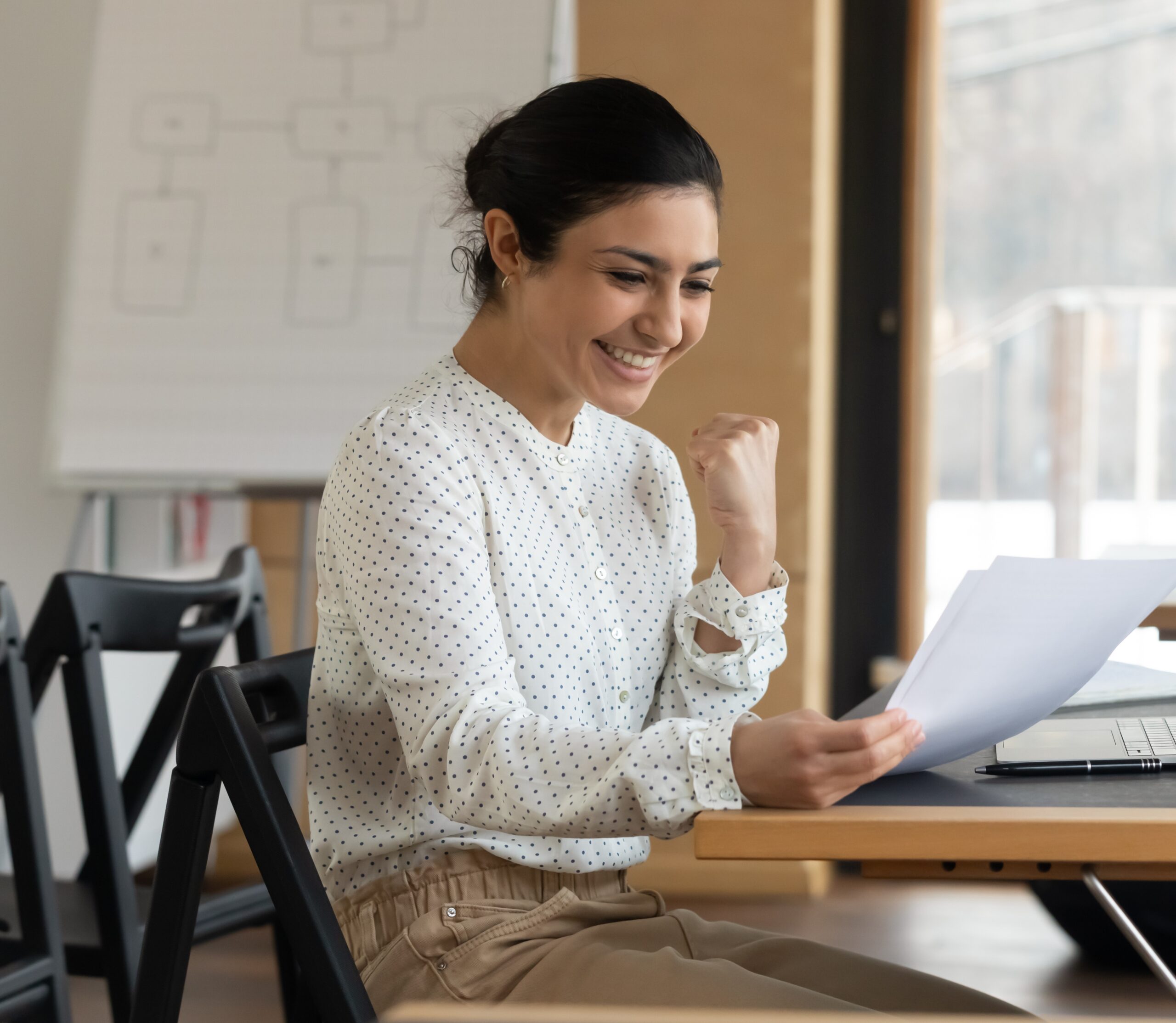 young white women sitting at her desk smiling reading a document