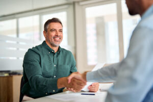 man in green button up shirt shaking hands with banker