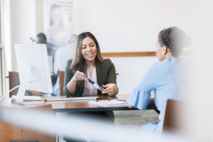 A woman shows a document to another woman