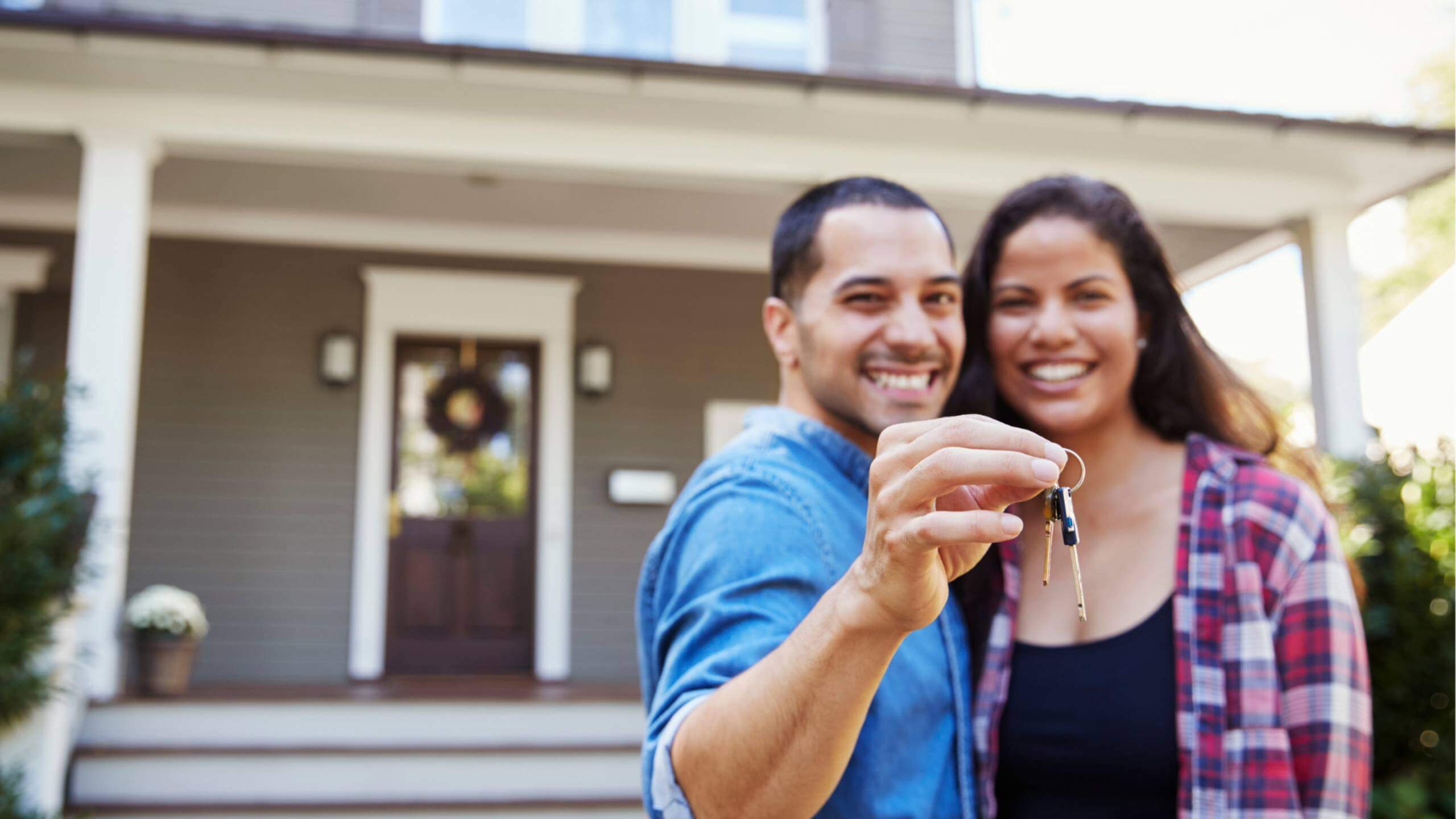 Young couple holding the keys outside of their new home