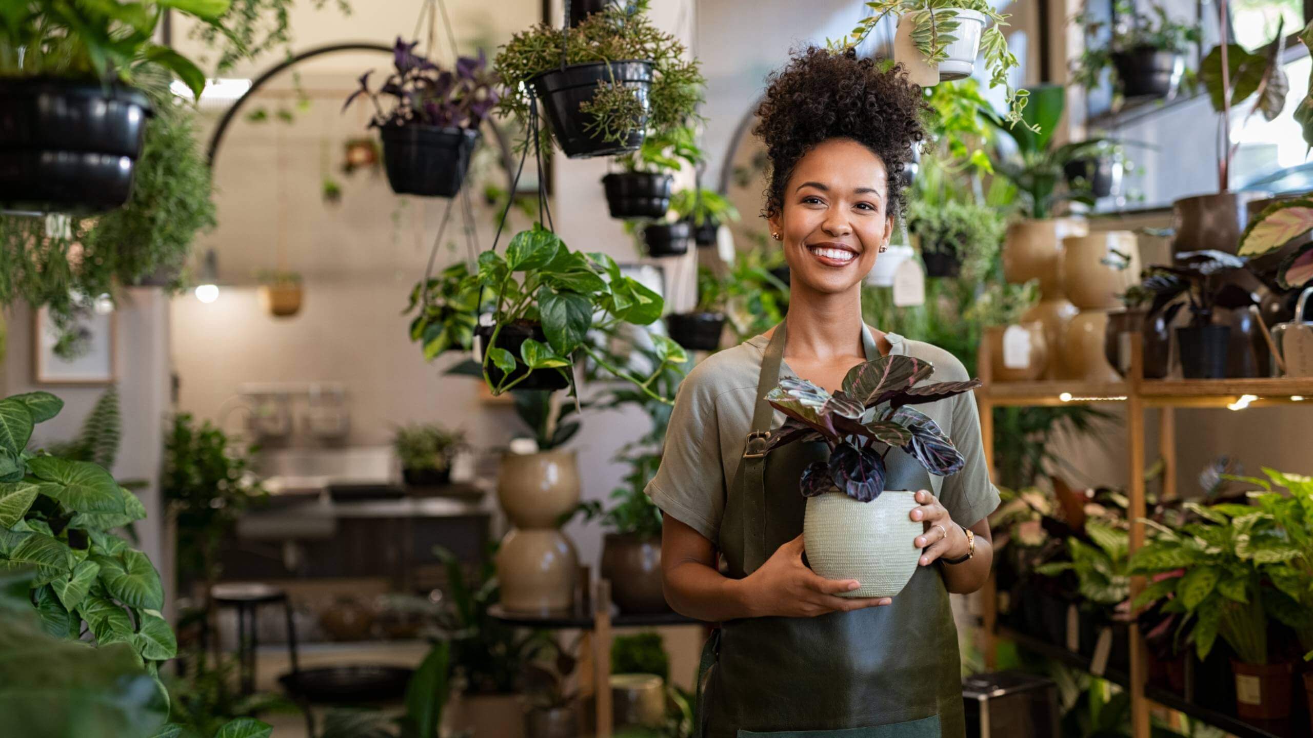 A female plant store owner standing with plants