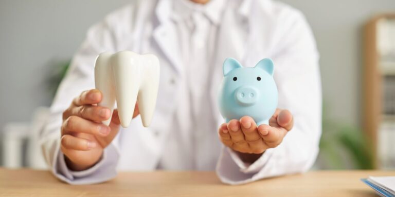 Maryland dentist doctor sitting at the desk in dentistry clinic and holding piggy bank and healthy white tooth in hands